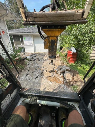 A concrete driveway being demolished with a concrete breaker.