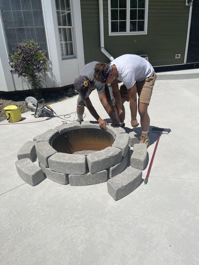 Installation progress of a fire pit on a concrete patio.